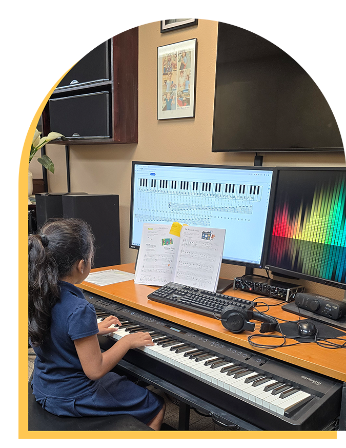 A young girl with long dark hair plays an electronic keyboard in a music classroom during music lessons Westchase, with sheet music in front of her and two large monitors displaying musical notes and a colorful soundwave.